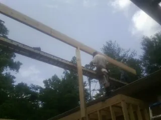 Carpenter setting a ridge beam over a new addition frame — Ice Dam Removal by Roofing Brothers in Indianola