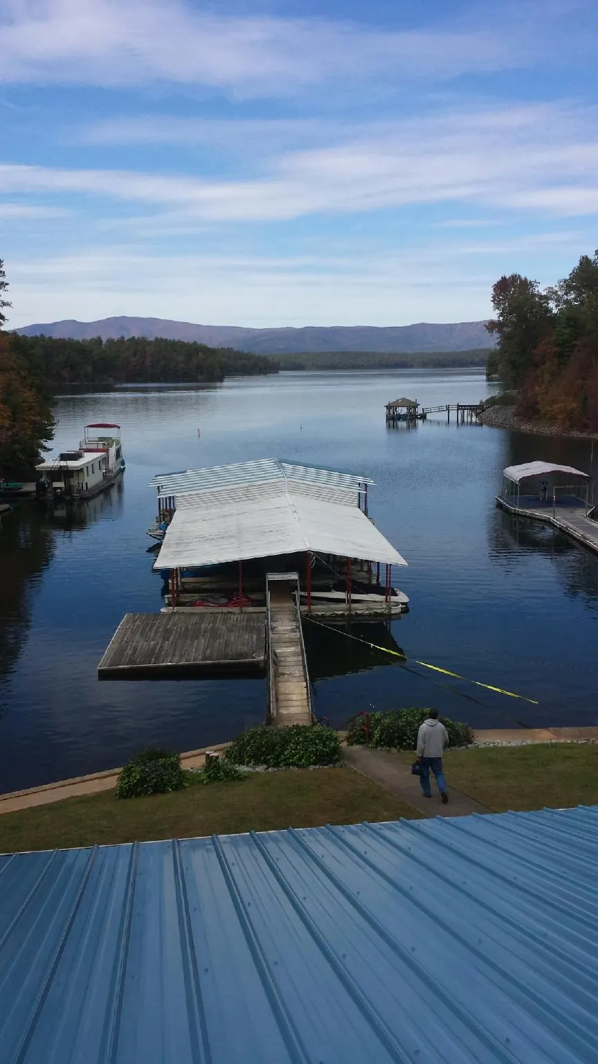 View across a lake from a newly installed blue metal roof in Indianola